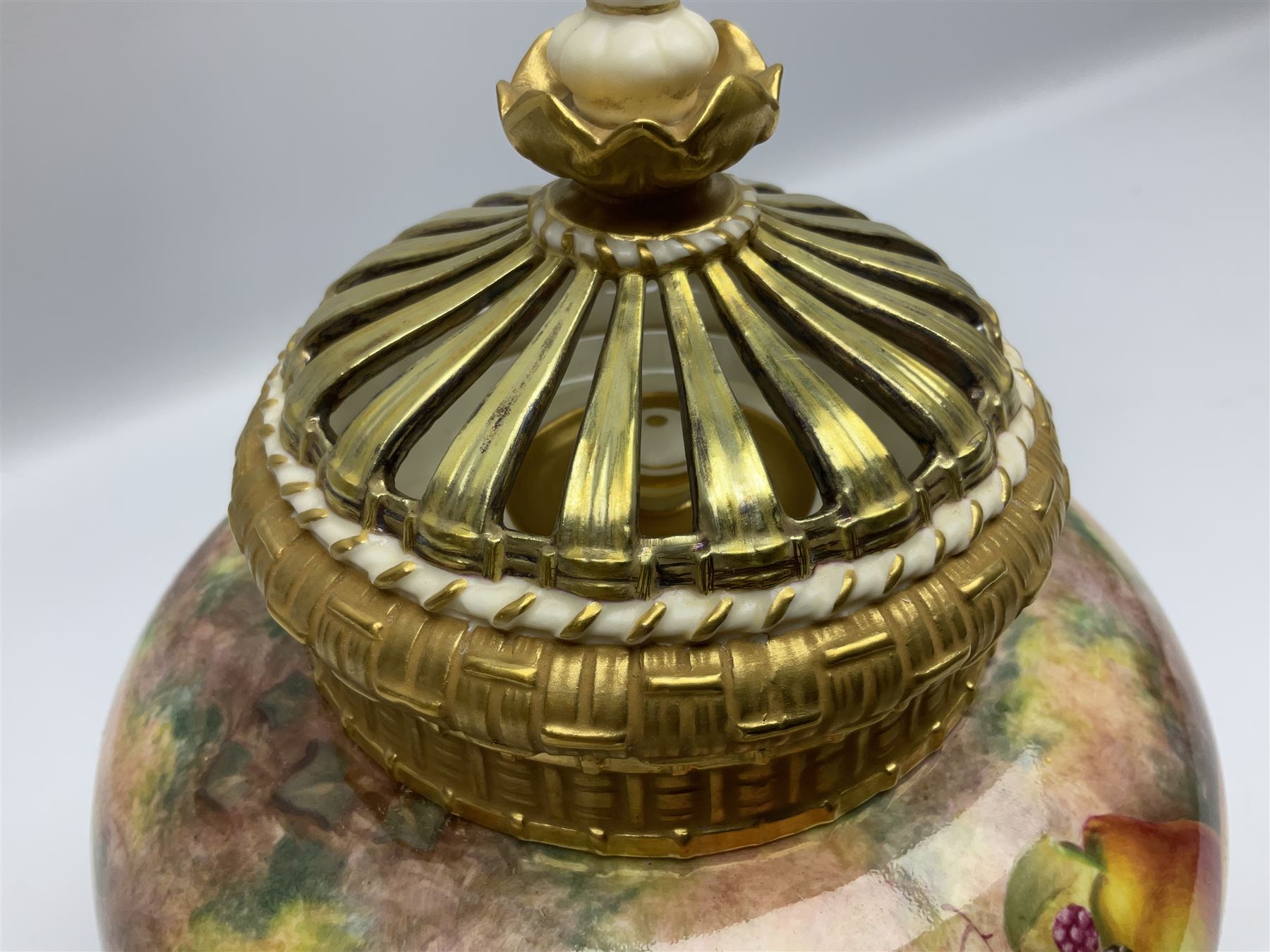 Mid 20th century Royal Worcester potpourri vase and cover decorated by Alan Telford, of ovoid form with inner cover and pierced gilt outer cover with bud finial, upon short gilt circular foot, the body part moulded with basket weave bands in gilt and bronze, and hand painted with a still life of fruit upon a mossy ground, signed Telford, with black printed mark beneath and painted shape number 1286, H25.5cm