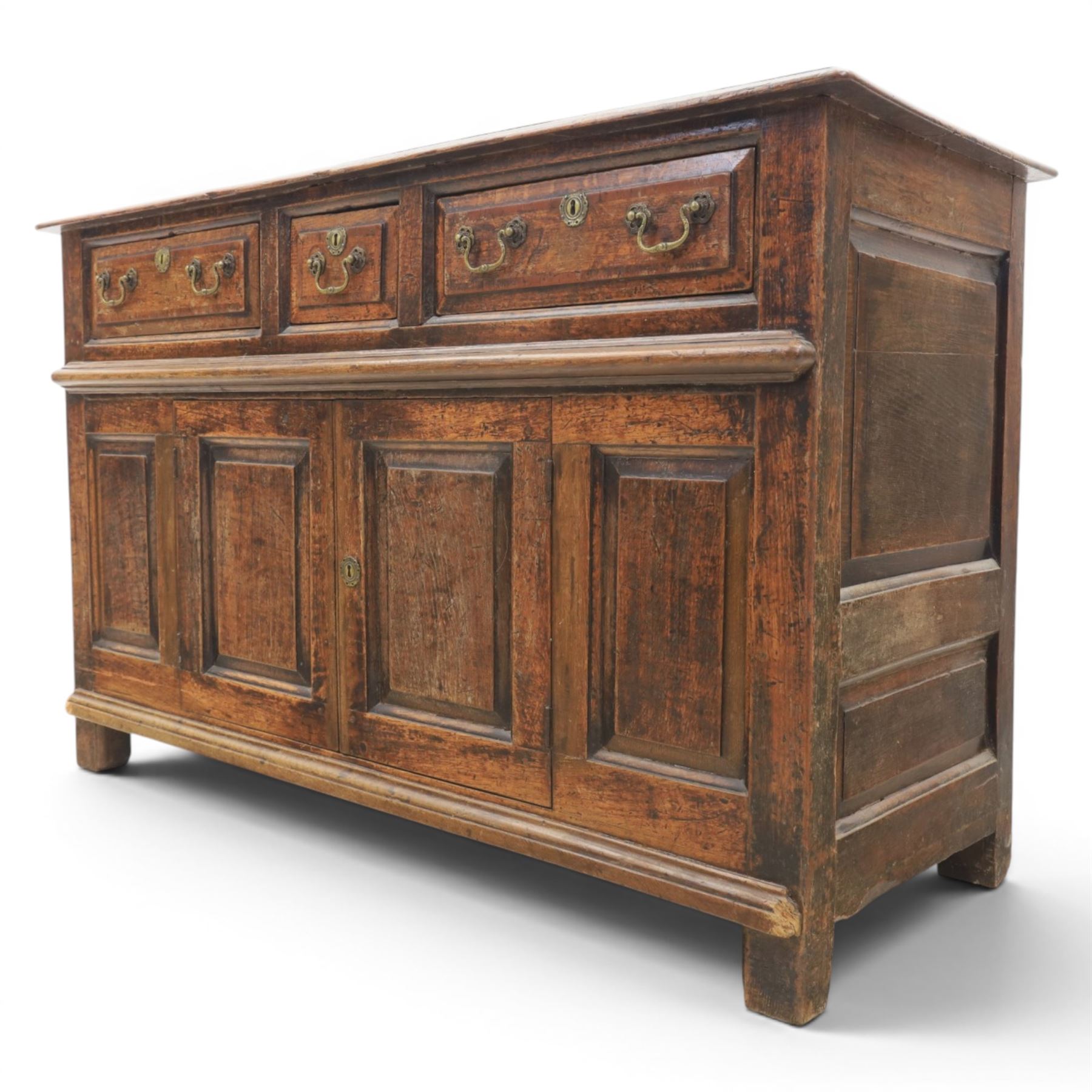 George III oak dresser base, rectangular top with moulded edge, three fielded panelled drawers with brass swan neck handles, over four fielded panelled front with the central two cupboard doors, raised on stile supports