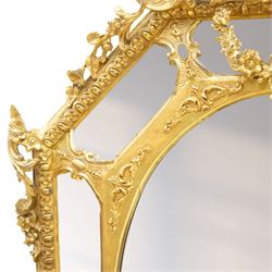 Late 19th century French giltwood and gesso wall hanging cushion mirror, the pierced foliate rocaille pediment extending acanthi C-scrolls and trailing bellflowers, over a floral garland and cartouche moulded rails, the central oval bevelled plate surrounded by further bevelled cushion mirrors, with out-scrolling pierced motifs flanking the floral egg-and-dart moulded outer edge, over a pierced foliate cartouche terminal