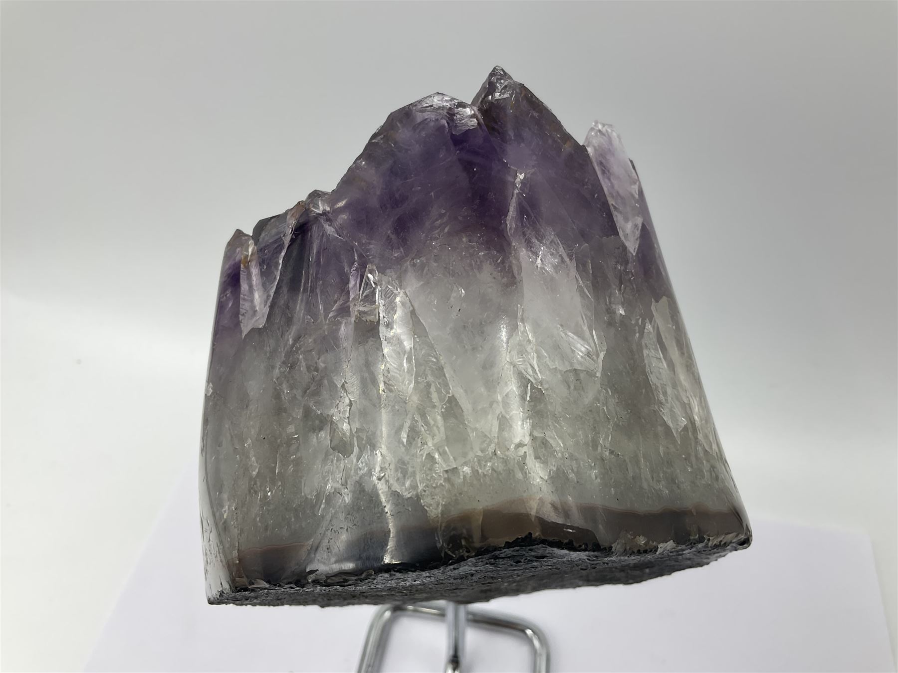 Amethyst crystal geode cluster, with large well-defined crystals, upon a metal stand, H21cm