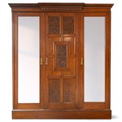 Late Victorian oak and burr oak three-section mirror wardrobe, central door with three carved panels with shell and acanthus decoration, fitted with four drawers and four tray drawers, linen sides with bevelled mirrored panel doors with hanging space, plinth base, and dental cornice