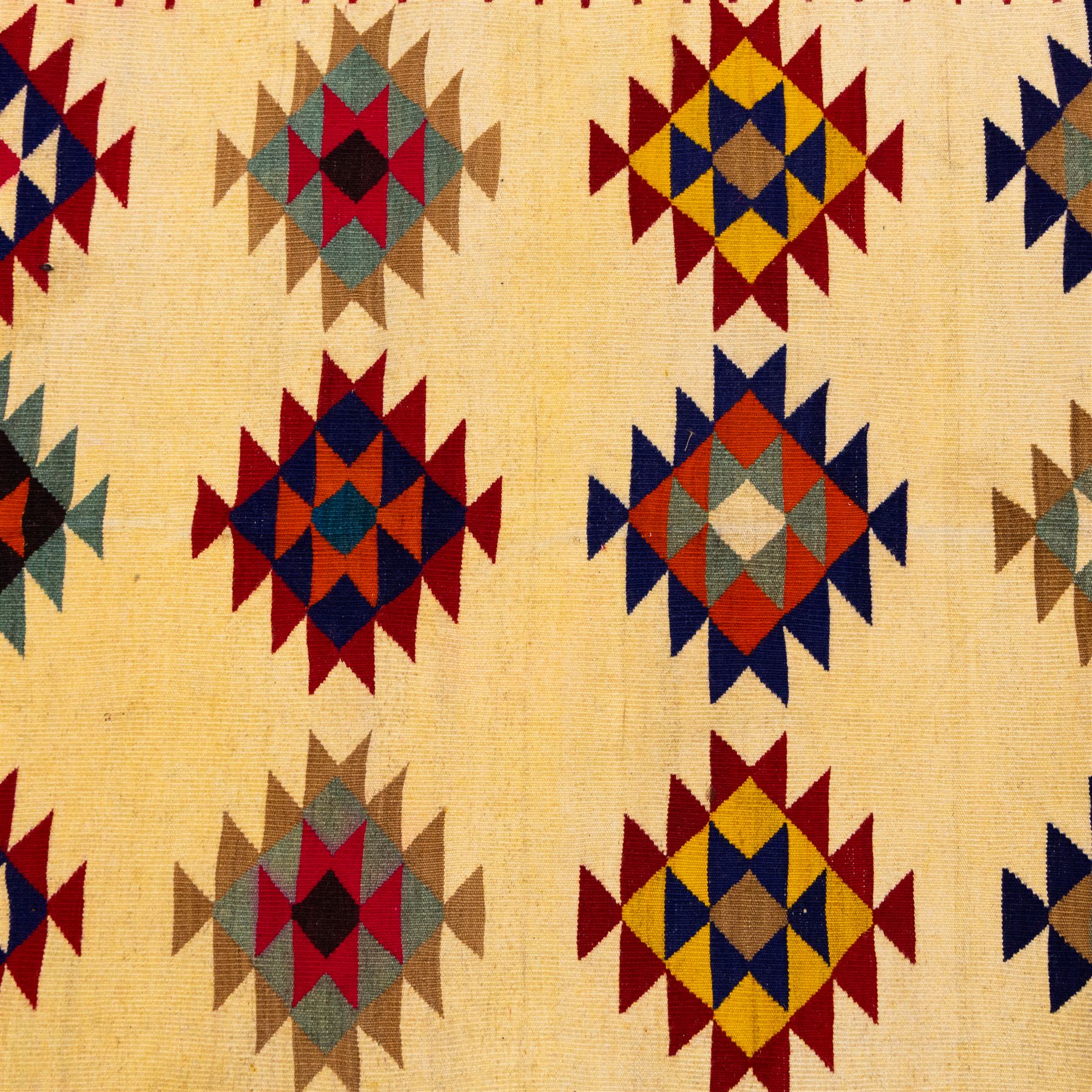 South West Persian Qashqai flatweave kilim, ivory field decorated with rows of multicoloured stepped diamond medallions composed of angular geometric motifs, enclosed by bold polychrome borders of triangular devices and stylized geometric, ornamentation, with fringe ends 