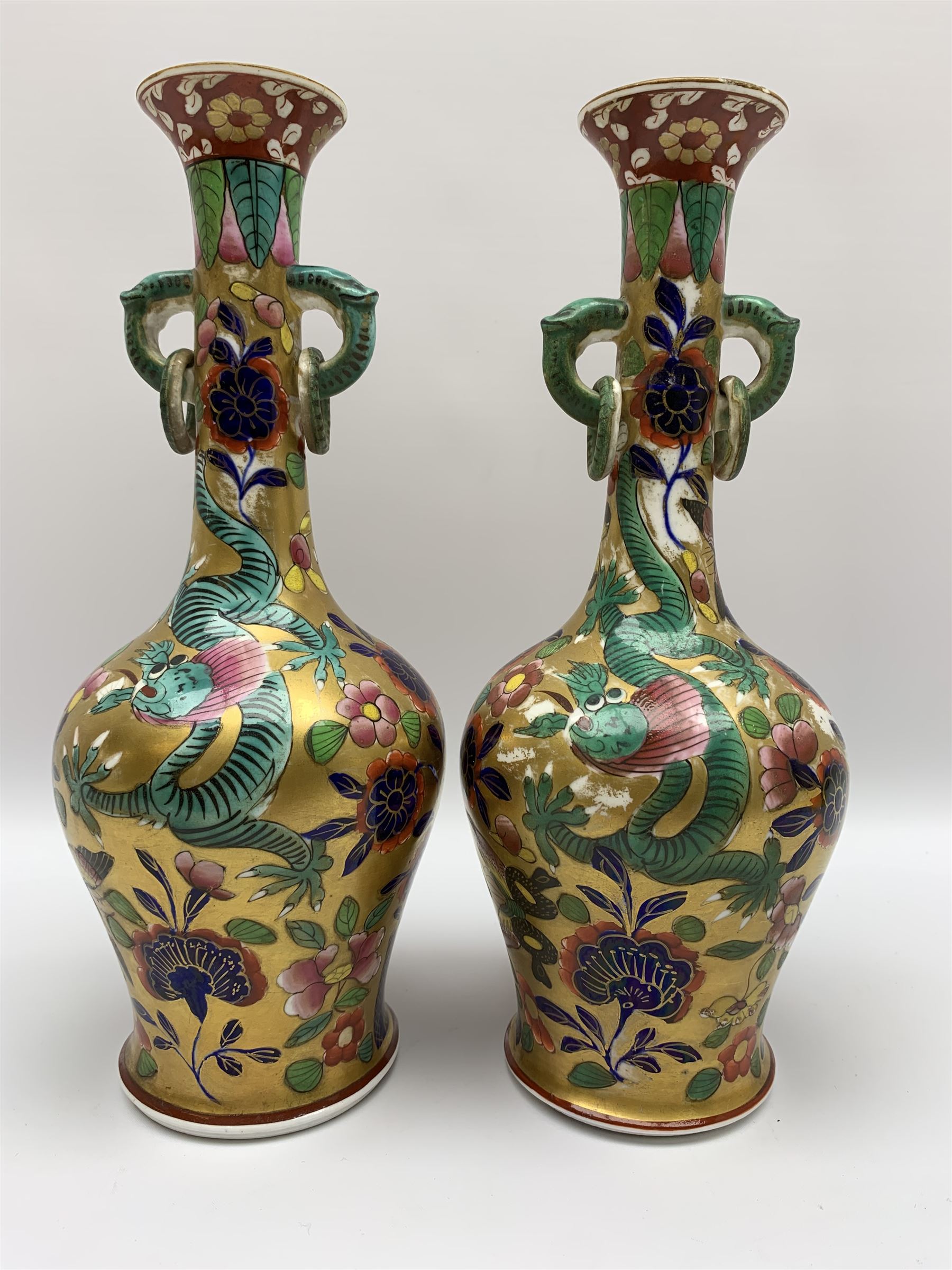 Pair of early 19th century Miles Mason vases, the baluster bodies with tall slender necks supporting twin stylised trunk handles with rings, decorated with Chinese dragons, butterflies, and blossoming flowers against a gilt ground, with spurious Chinese marks beneath in iron red, H27.5cm