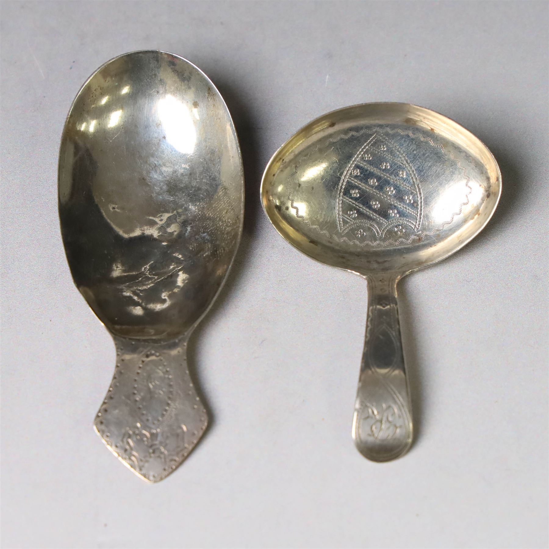 Two George III silver caddy spoons, the first example with oval bowl and flat handle with engraved initial, hallmarked Birmingham 1796, makers mark probably IT, the second with oval bowl, curved handle with shield and initial engraving, hallmarked George Smith III, London 1783