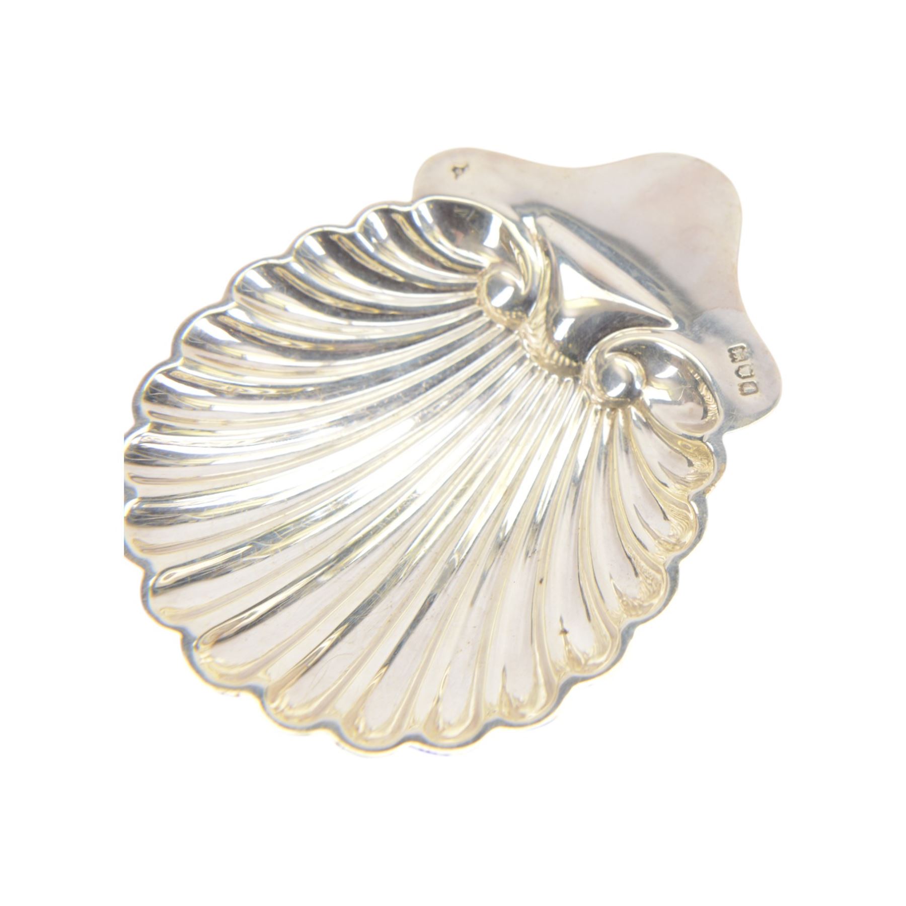 Edwardian silver shell butter dish, upon three bun feet, together with a matching shell spoon engraved with initial, both hallmarked Josiah Williams & Co, London 1906 and 1914, together with an Edwardian milk jug, open sucrier and sugar tongs, the jug and bowl of circular part fluted form with bead rim, hallmarked Mappin & Webb Ltd, Sheffield 1902, both sets contained within fitted tooled leather boxes with silk and velvet lined interiors