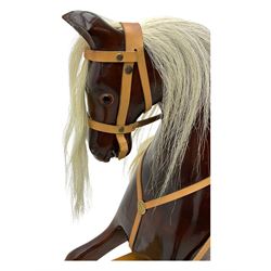 Contemporary carved wooden rocking horse, with leather saddle and bridle, horsehair mane and tail, raised on a pine stand with swing iron supports
