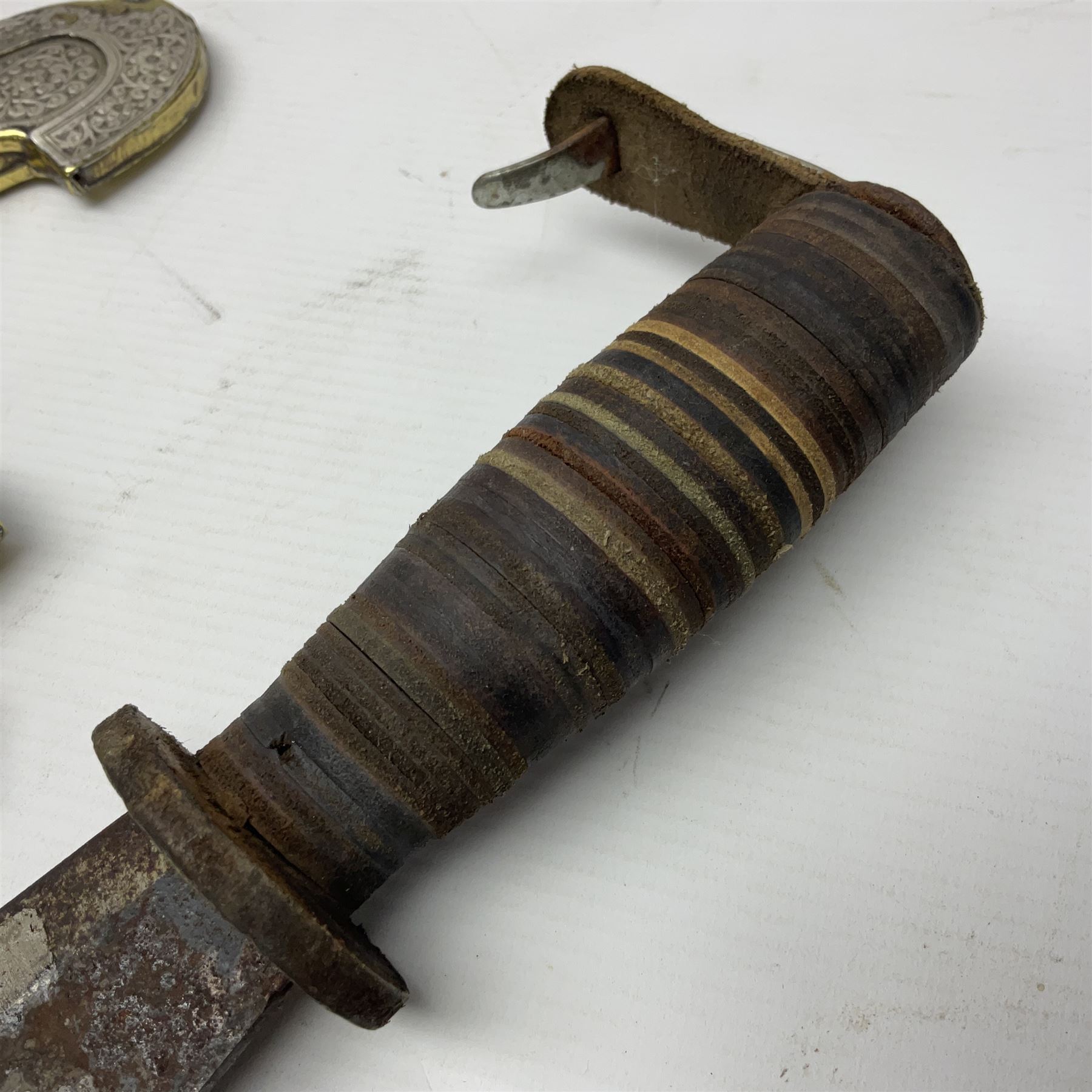 Moroccan jambiya dagger with 24.5cm plain curved blade stamped LONDON to the ricasso area, the hilt and scabbard overlaid with plain sheet brass to the back and ornate silver coloured metal to the front; waisted grip and arched pommel; two pyramid mounts to the scabbard L41cm overall; large billhook with curving blade and stacked leather washer grip; and a reproduction halberd blade (3)