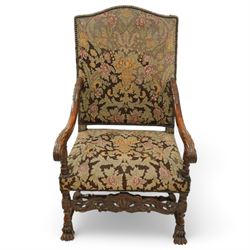 Baroque design walnut framed open armchair, arched cresting rail over acanthus carved shaped arms with scrolled terminals, upholstered in floral pattern fabric with stud bands, shaped and pierced middle rail carved with curled acanthus leaves and flower heads, on turned and block front supports terminating to paw feet, united by turned stretchers 