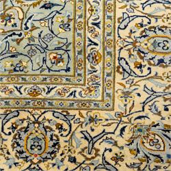 Central Persian Kashan hand-knotted carpet, pale celadon blue ground, decorated with an all-over central floral and foliate design with rosette medallion incorporating scrolling vine work, palmettes, and stylized blossoms  highlighted in tones of indigo, ivory, gold, and powder blue, enclosed by a cream ground border, flanked by multiple guard stripes, with cotton fringe ends 