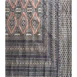 Large Persian Bokhara wool rug, the field decorated with repeating gul motifs in lozenge medallions across a dark ground, enclosed by multiple geometric borders in indigo, ivory and terracotta, from the region of Baluchistan