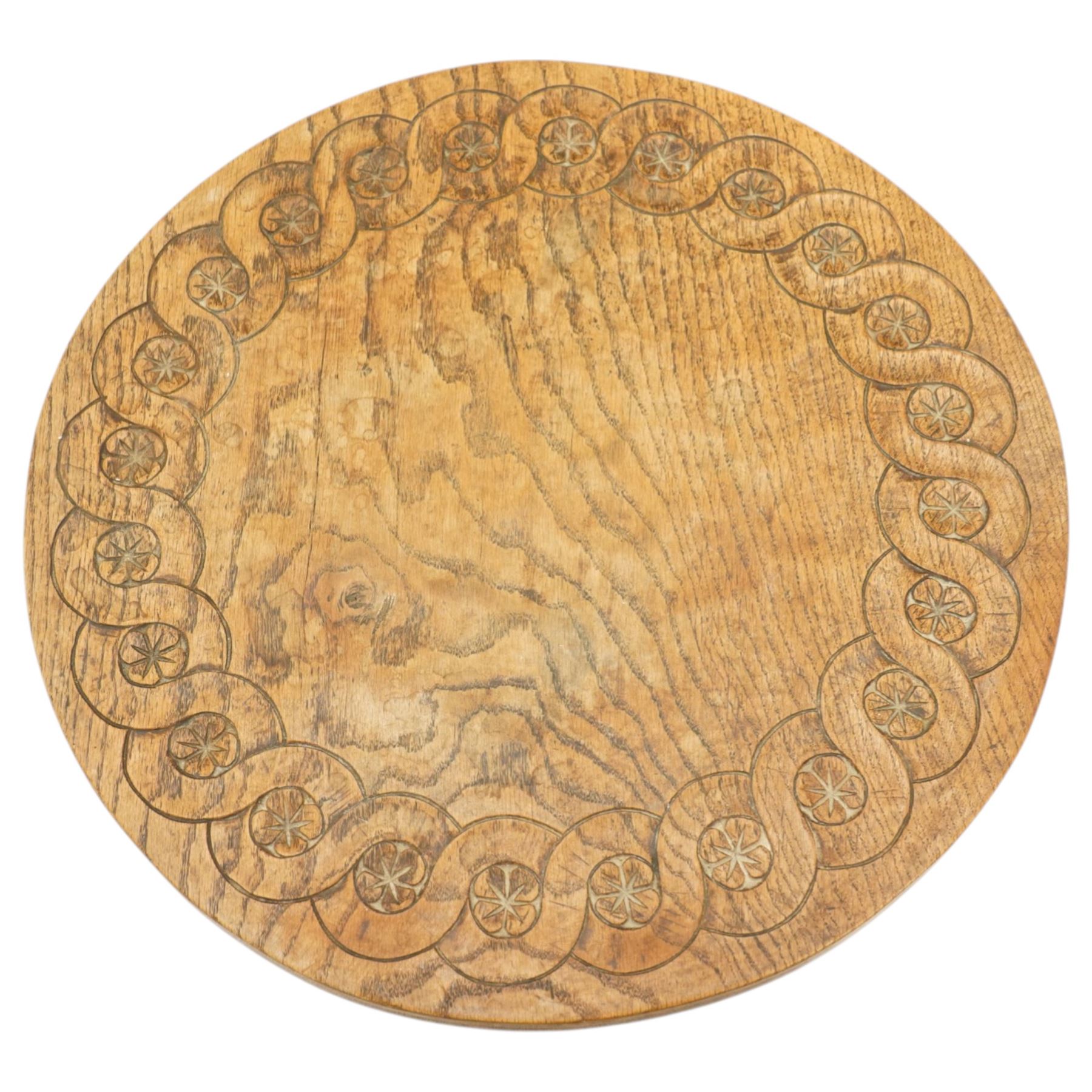 Gnomeman - oak circular stool, the top carved with continuous rosette and scrolling border, raised on three splayed supports, one leg carved with gnome signature, by Thomas Whittaker of Littlebeck