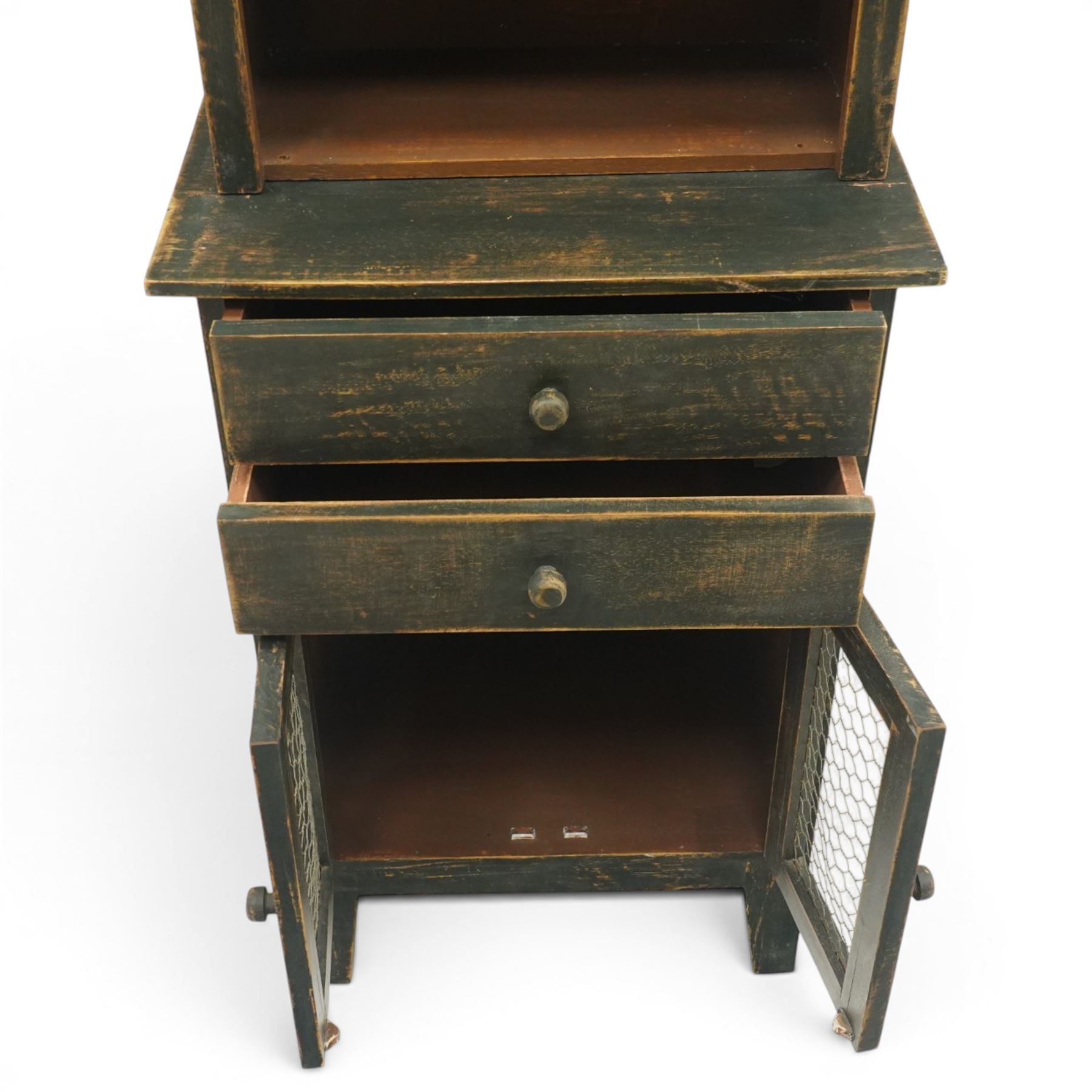 20th century pine kitchen cabinet in a green painted finish, top section with upper door with wire front above a recessed shelved area, the lower section with two drawers and twin wire fronted doors, raised on tapered supports