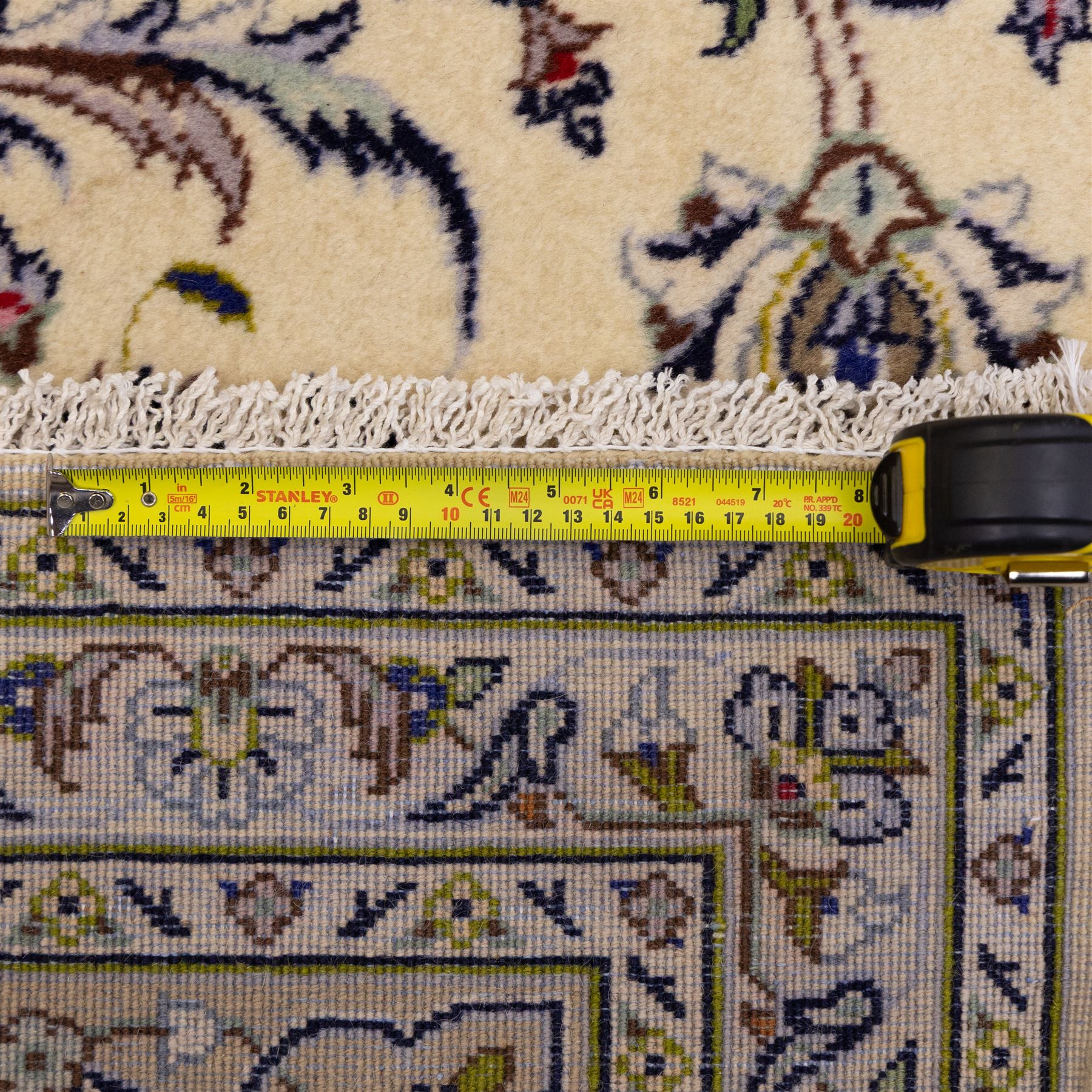 Central Persian Kashan hand-knotted carpet, ivory field densely decorated with an all-over design of scrolling floral vines and palmettes, framed by multiple borders with continuous floral meander and rosette motifs, in a palette of indigo, ivory, soft blue, sage green, rose and ochre tones, with cotton fringe ends 