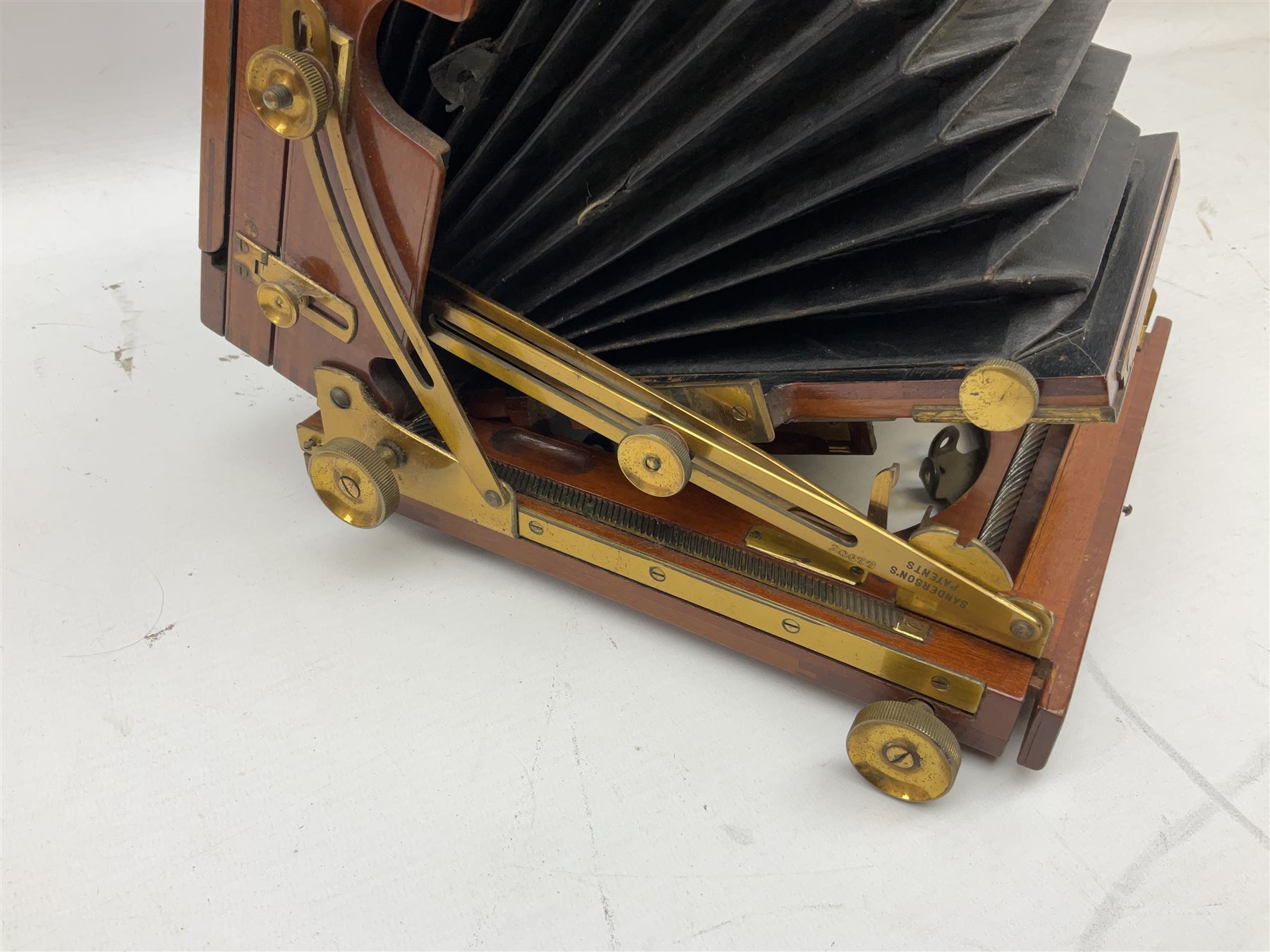 Ensign 'The Sanderson' folding plate camera in mahogany and lacquered brass, field model with canvas wrapped box, two mahogany photographic plates, 'Busch rapid Symmetrical F:8' lens,  and a wooden tripod 