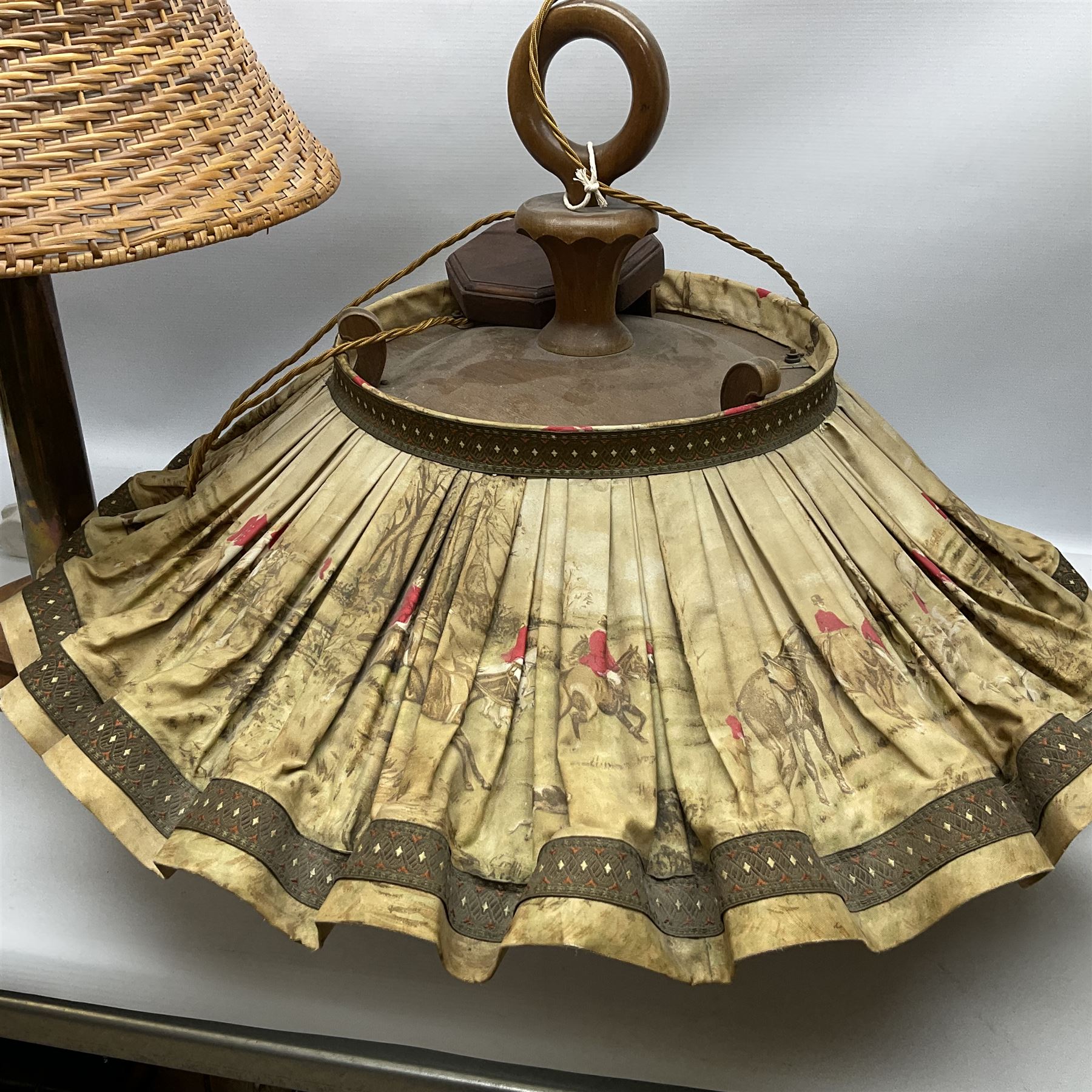 Trench Art shell lamp upon a stepped circular base, together light fitting with an umbrella shade depicting a hunting scene and a wicker lamp shade