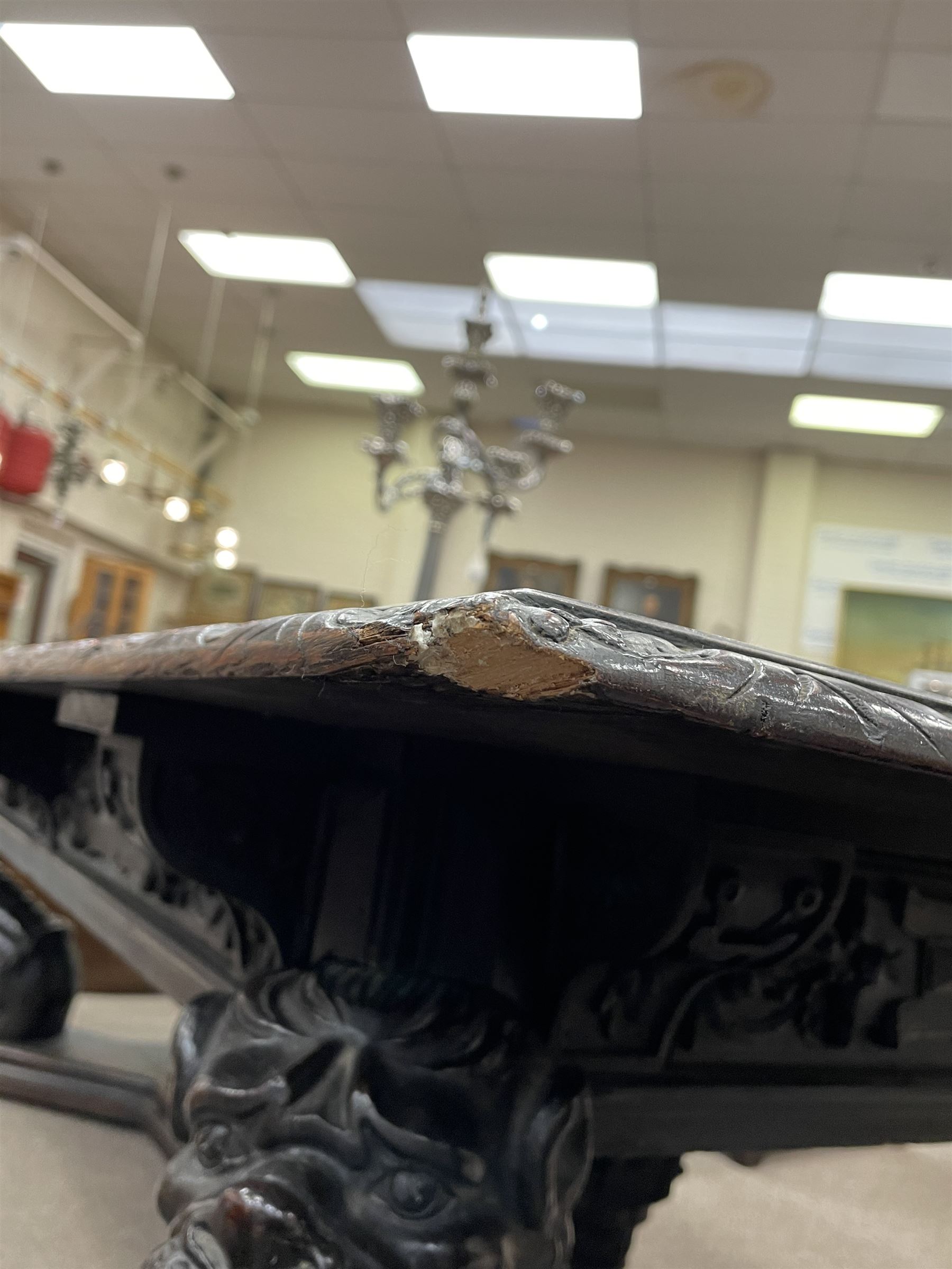 Large 19th century carved oak library table, the rectangular top with lunette carved edge over cartouche panelled and carved  scroll frieze, the central tapering rectangular support relief carved with masks and garlands, on four carved seated lion supports at each corner, on flat angular stretcher with recessed castors stamped ‘Bartholomew & Fletcher, London’