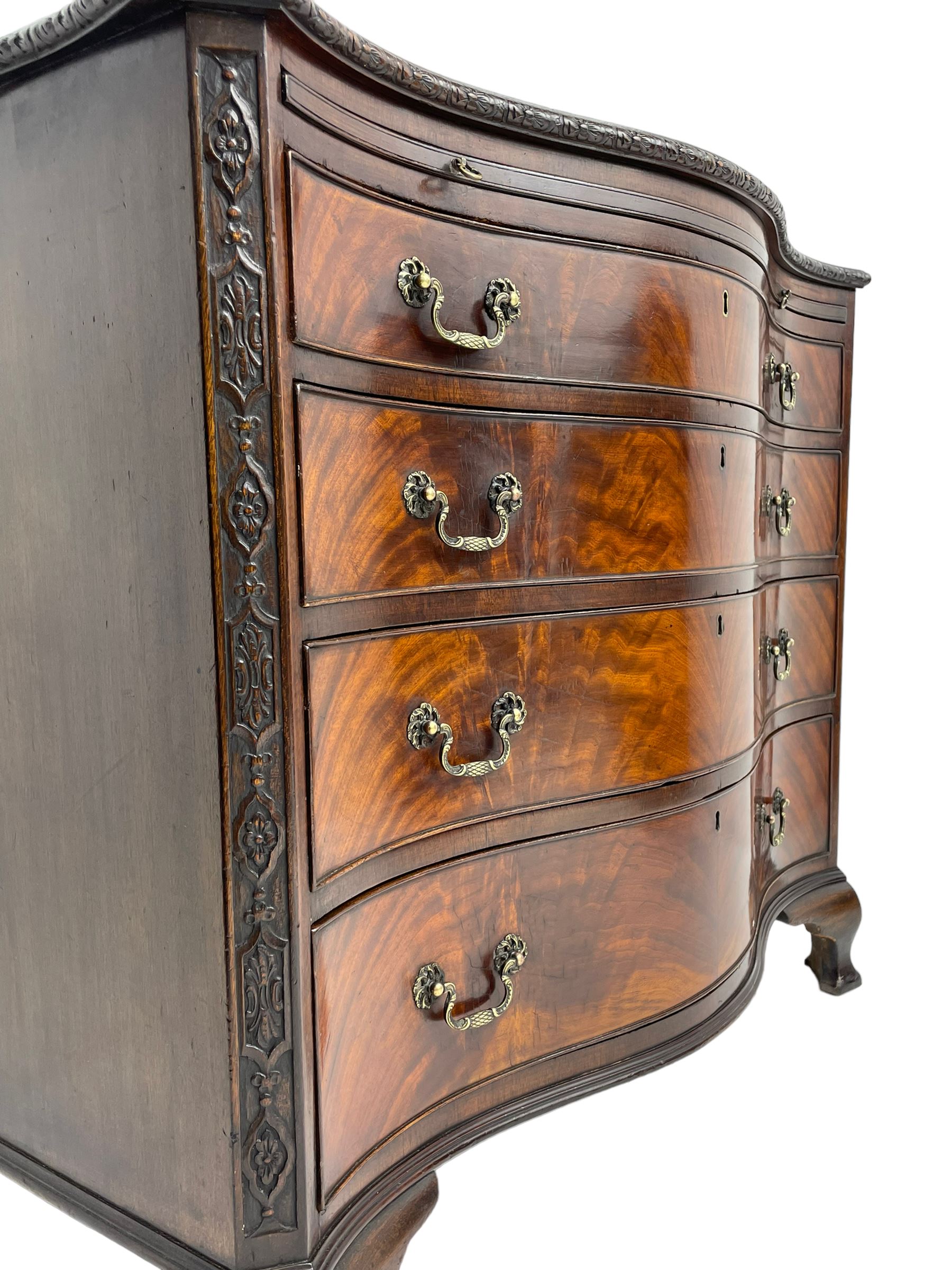 Chippendale design serpentine chest, shaped moulded top carved with repeating flower head motifs, fitted with brushing slide over four graduating drawers, pierced and foliate moulded handle plates with scrolled swan neck handles, canted upright corners carved with flower heads and strapwork, on canted ogee bracket feet