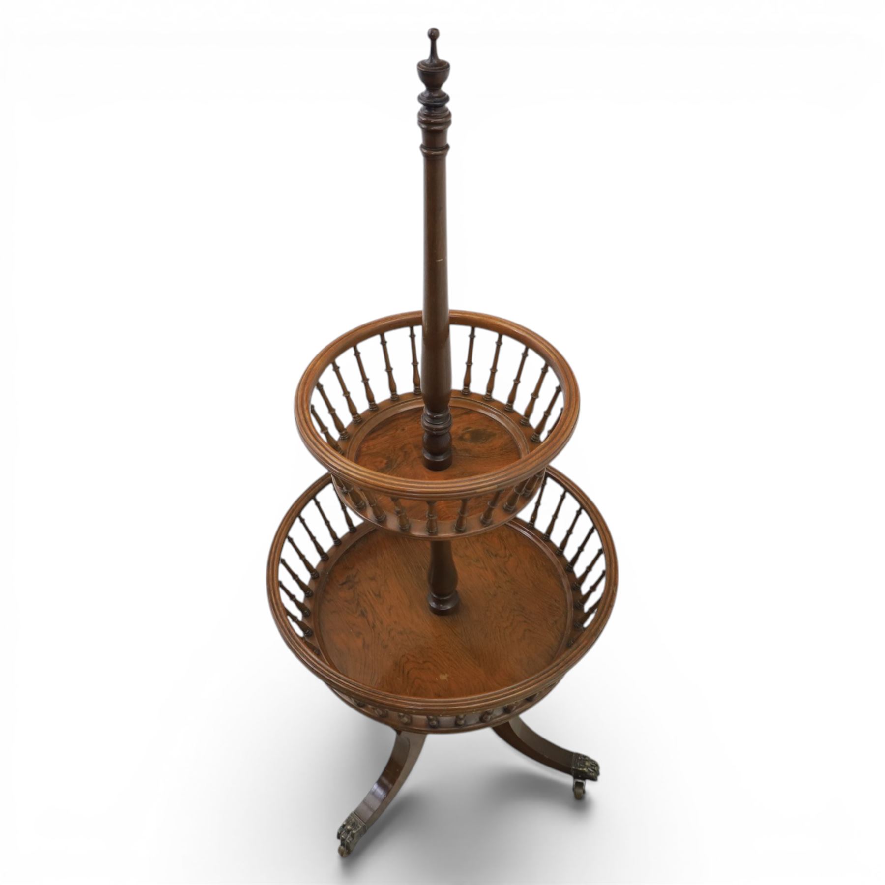 Regency style oak two-tier dumb waiter, with turned finial above central column support, two circular spindle-galleried basket tiers, raised on downswept tripod supports with brass caps and castors