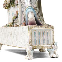 Large19th century  German porcelain mantel clock with white dial and striking movement, the case with a standing figure of Flora resting on a pillar with floral applied decoration, the base painted eith landscape and floral panels on paw feet H77cm W43cm