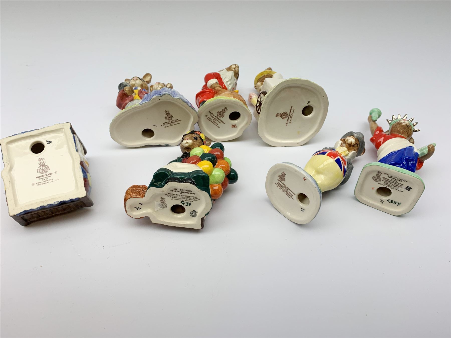 A group of seven Royal Doulton Bunnykins figures, comprising Father, Mother & Victorian Bunnykins DB68, Santa Bunnykins DB17, Uncle Sam Bunnykins DB50, Bunnykins Sleepytime DB15, Old Baloon Seller Bunnykins DB217, Statue of Liberty Bunnykins DB198, and Ice Cream Bunnykins DB82.