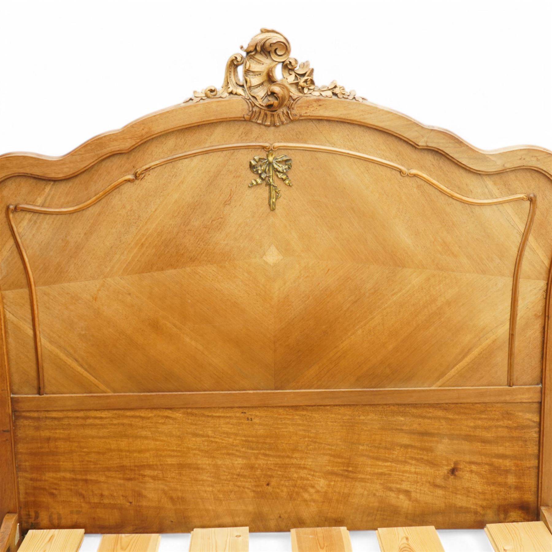 Mid-20th century French walnut small double 4' 2'' bedstead, shaped and moulded headboard with shell and curl acanthus leaf carved pediment with extending flower heads, quarter-matched veneers decorated with applied mouldings and cast gilt metal ribbon tie 