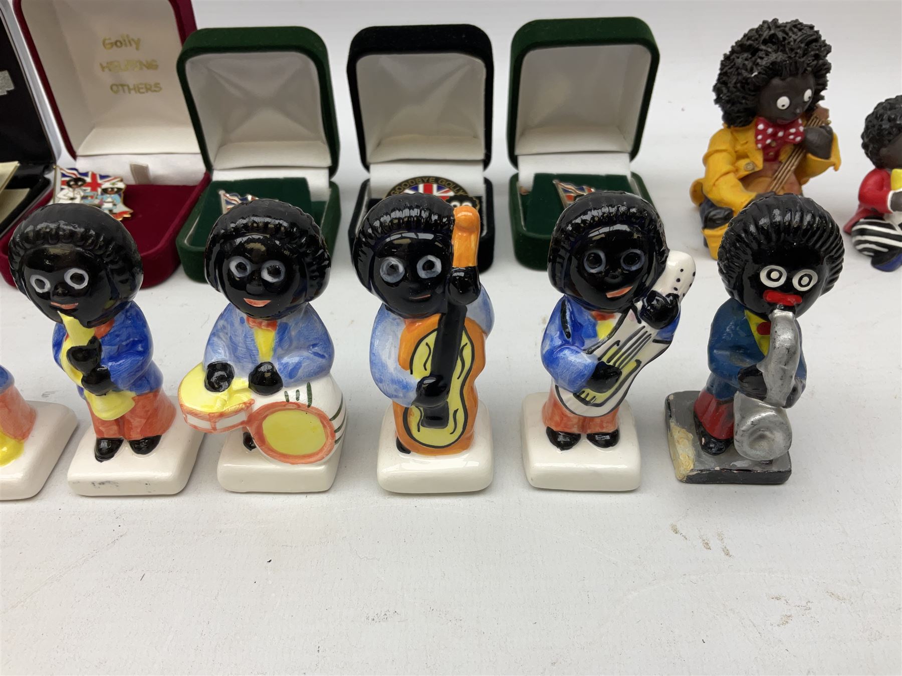 Eight ceramic Golly Band figurines marked Carlton Ware, together with four other Golly figures and five boxed badges