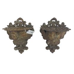 Pair cast iron wall mounted garden pot brackets in the form of putti, decorated with foliage and scrolls