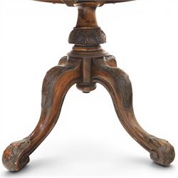 Victorian figured walnut oval loo tilt top table, raised on a heavily carved quatriform base with scrolled supports, terminating in castors