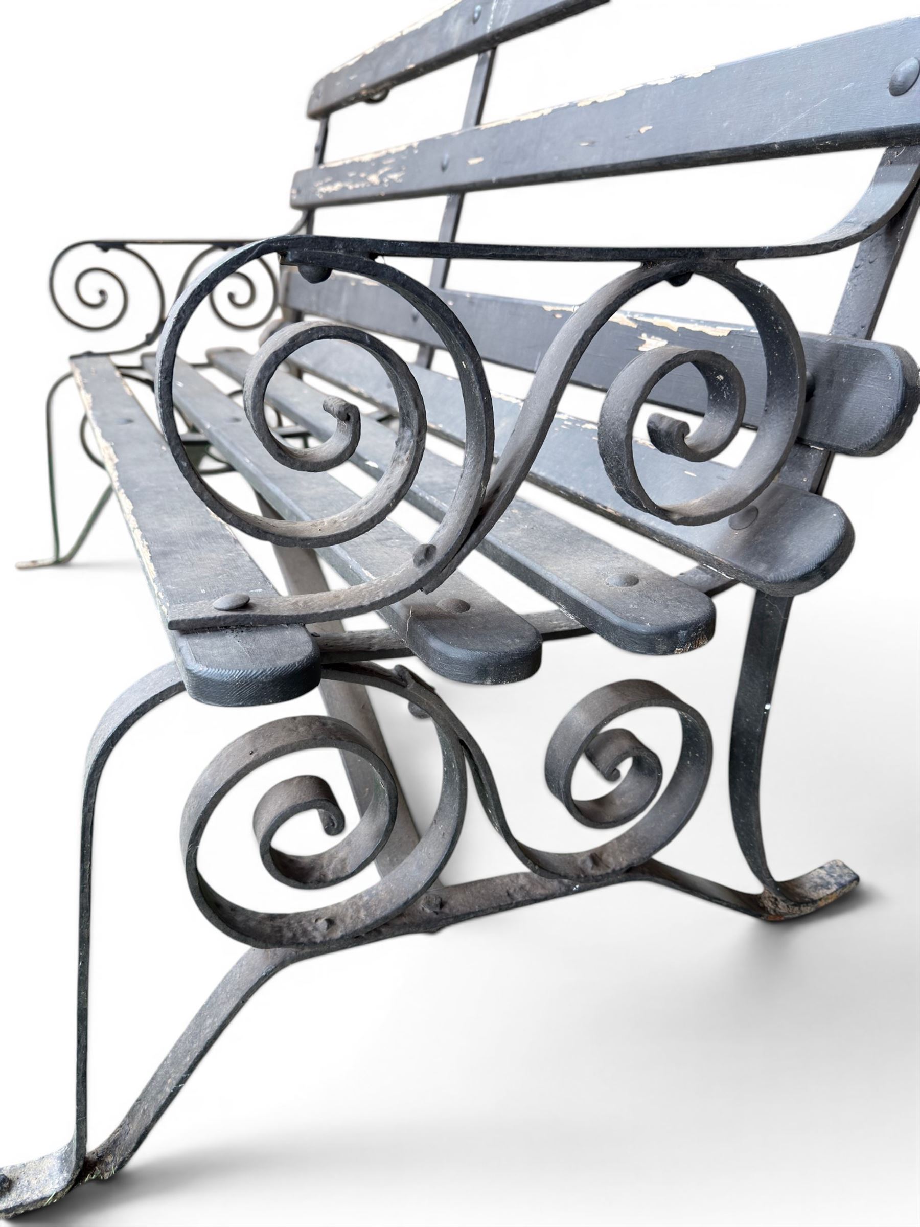 Coalbrookdale - rare pair of wrought iron and slatted wood garden benches, the twin wrought iron strapwork bench-ends formed of four scrolls over splayed feet, number 77 in the Coalbrookdale Castings Catalogue (see illustration)