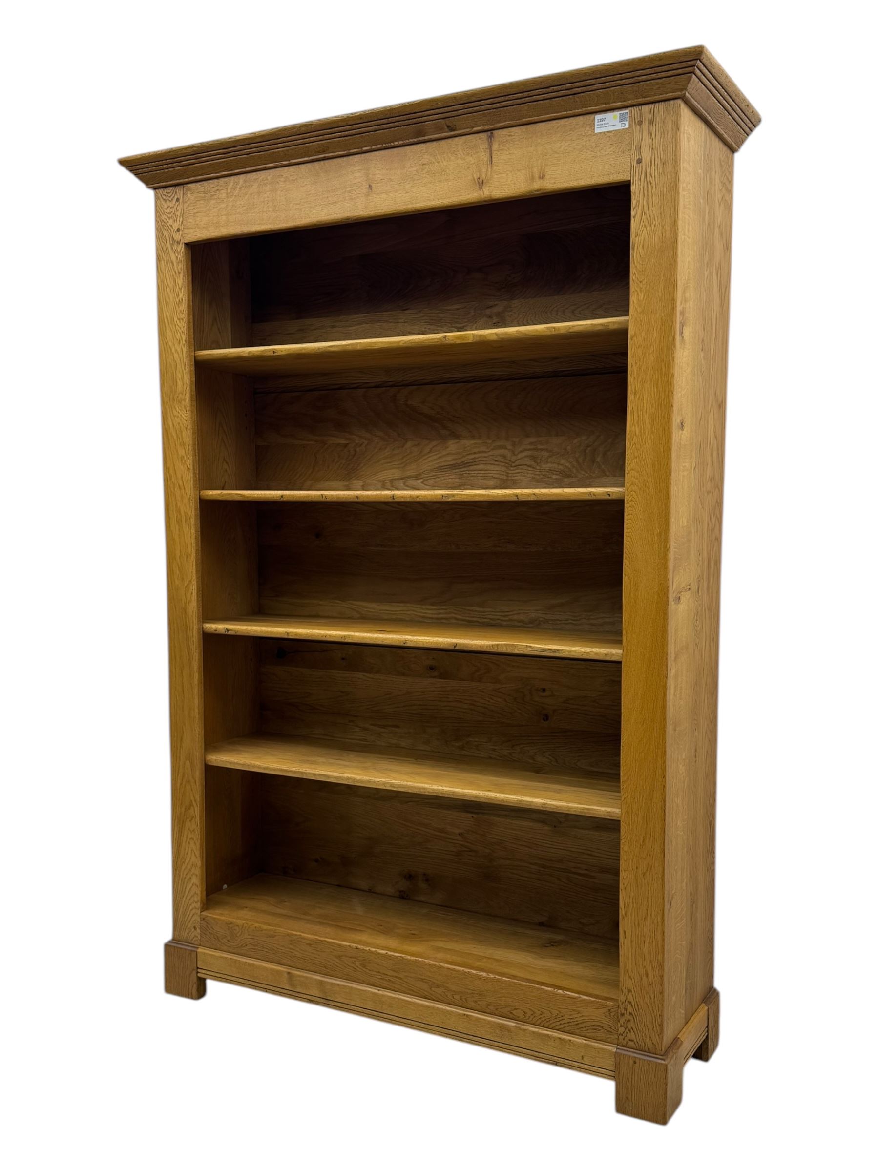 Contemporary French provincial design oak open bookcase, with projecting moulded cornice above a boarded back, fitted with four adjustable shelves, on bracketed plinth base
