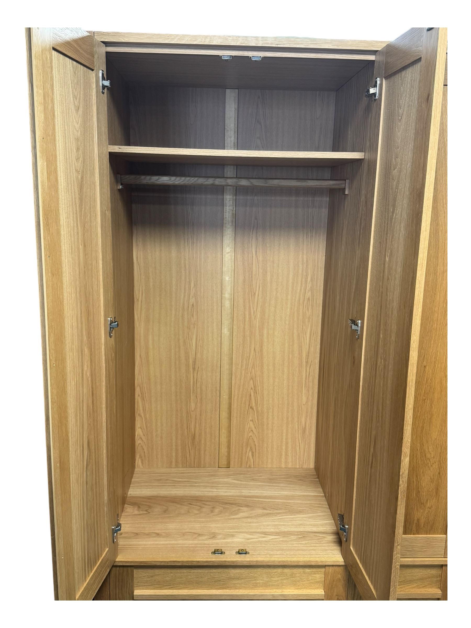 Contemporary light oak triple wardrobe, panelled doors with vertical linear design, left section enclosing hanging rail and single shelf, right section with adjustable shelves, over two drawers, on square stile supports