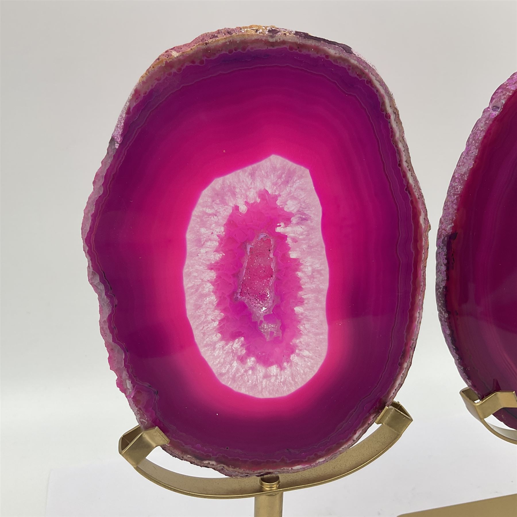 Pair of pink agate slices, polished with rough edges raised upon gilt metal stands, H20cm