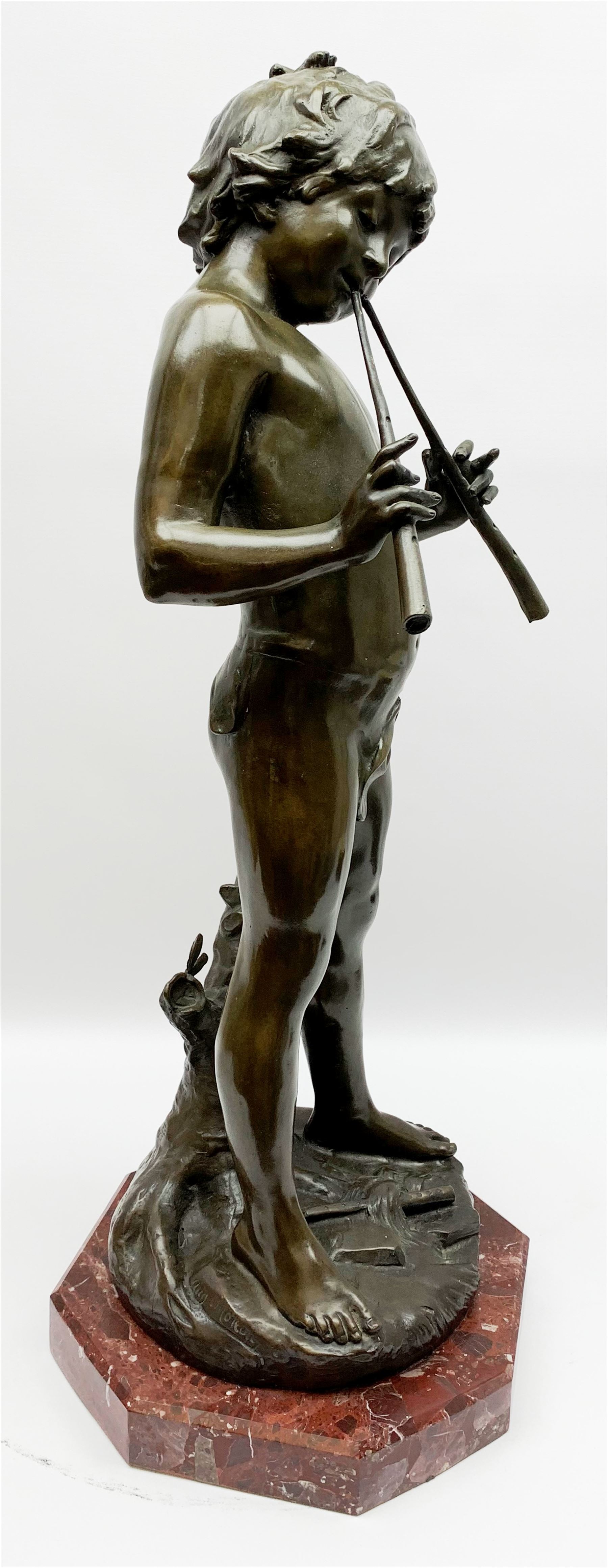 After Auguste Moreau (French 1834-1917): large bronze figure modelled as a young boy playing two pipes, standing upon a naturalistically modelled base detailed with tree stump and further pipe, signed Aug Moreau, upon octagonal red marble base, H72cm 