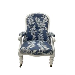 Late 19th century white painted armchair, spoon back with scrolled arm terminals and turned supports with castors, upholstered in button-back blue and white patterned fabric with sprung seat