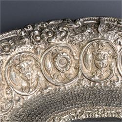 Late 19th/early 20th century continental silver serving bowl, of oval form, profusely embossed with scrolling floral and foliate decoration, with hammered finish to interior
