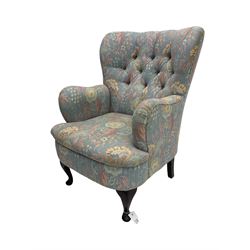 Mid-20th century wingback armchair, upholstered in soft blue floral patterned fabric with button-tufted backrest and curved arms and raised on cabriole supports