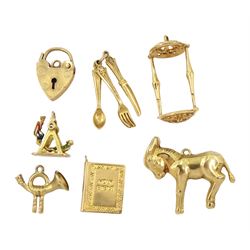 Seven 9ct gold pendant / charms including horn, swing boat, cutlery set and donkey