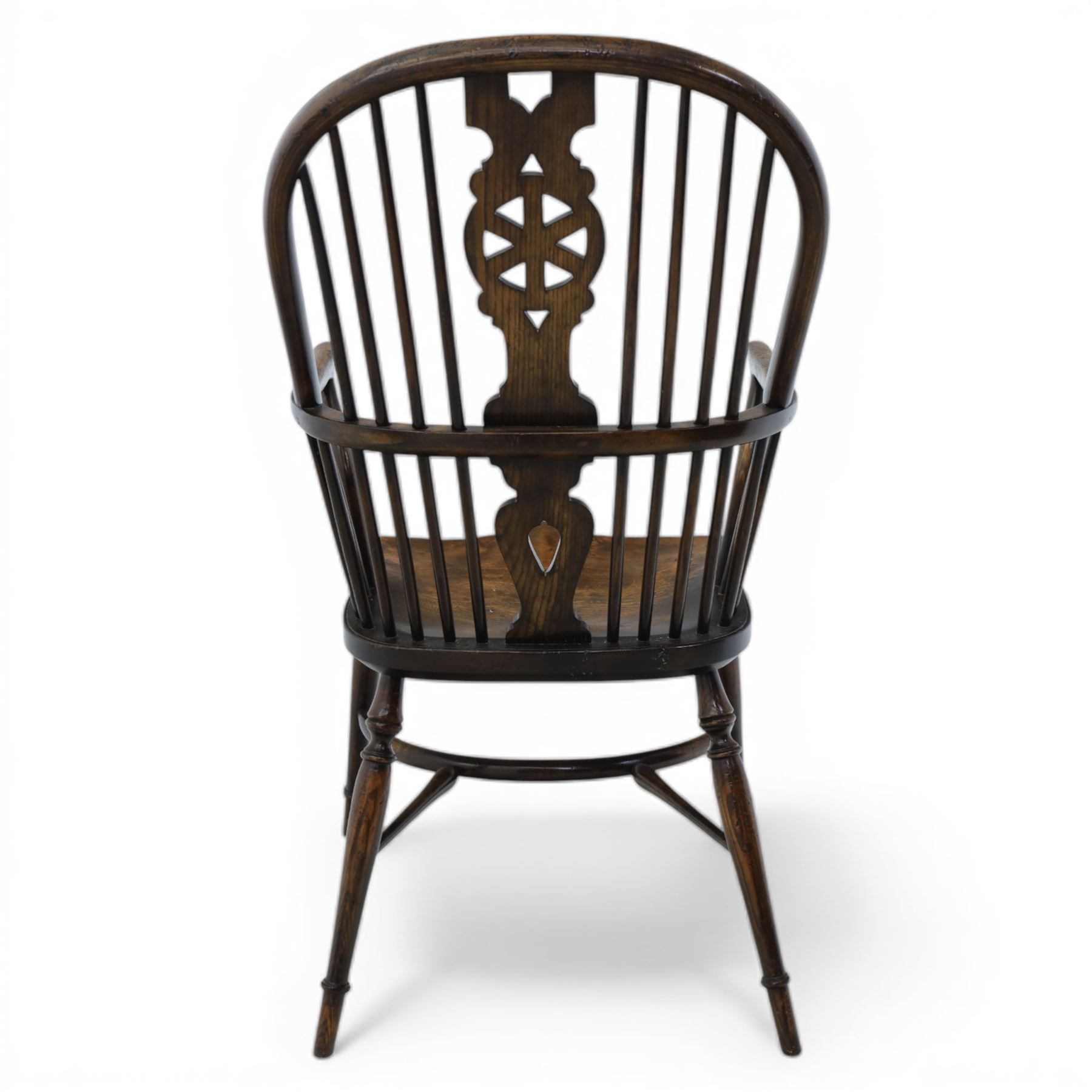 Late 19th century elm and beech high back Windsor armchair, the arched hoop back centred by a pierced wheel splat above a heart shaped lower piercing, with turned spindles and shaped arm rail, saddle seat, raised on turned legs united by a crinoline stretcher