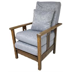 Arts & Craft oak reclining armchair with folding footstool, the upright splats pierced with stylised tulip decoration