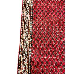 Persian design red ground runner, the field decorated with repeating Boteh motifs, five-band border (277cm x 74cm); Bokhara design red ground rug, decorated with a single row of Gul motifs (272cm x 69cm)