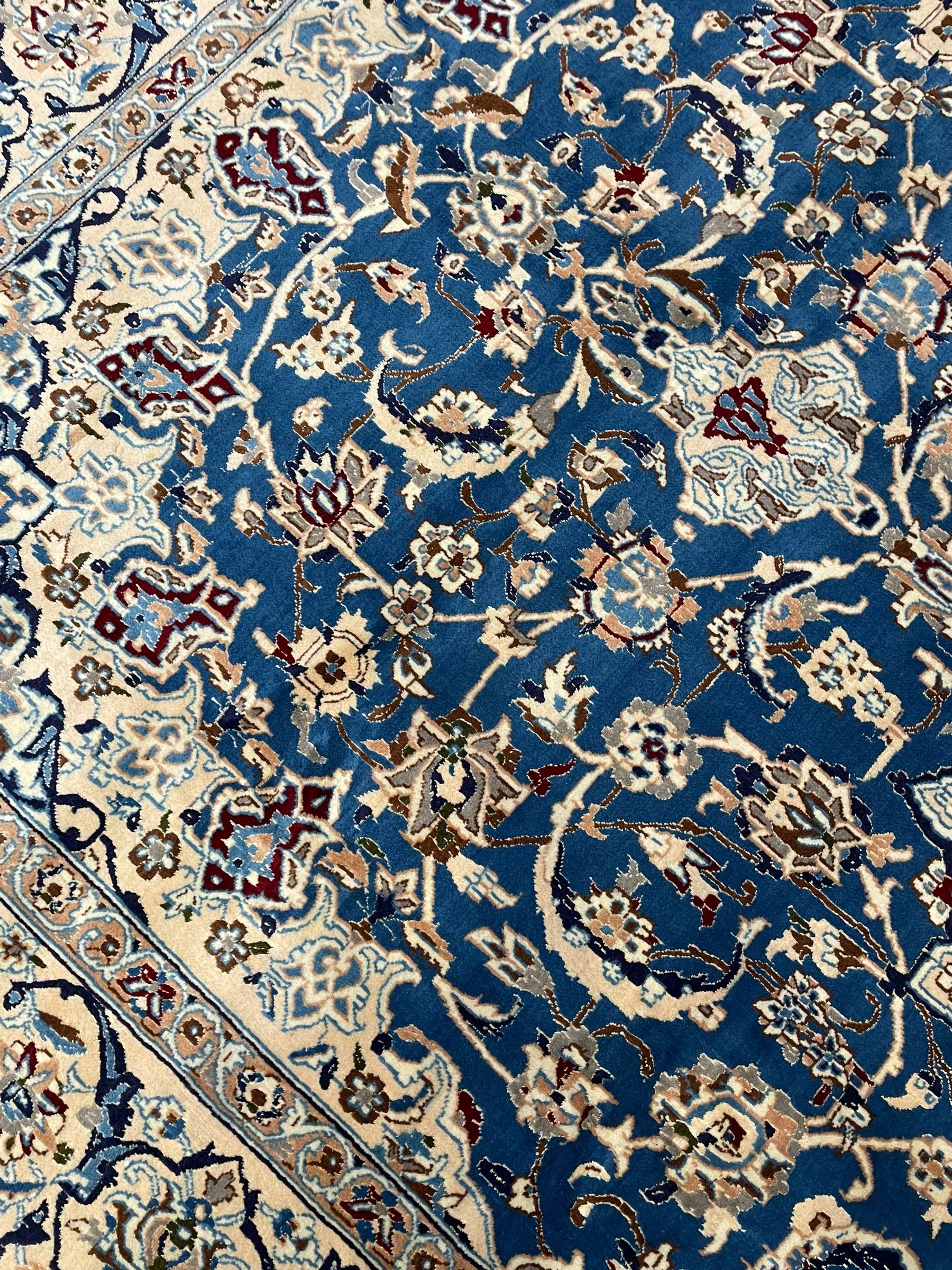 Persian Kashan blue ground rug, central floral rosette medallion within a field of swirling branches and palmettes, the border with trailing pattern interspersed with stylised plant motifs