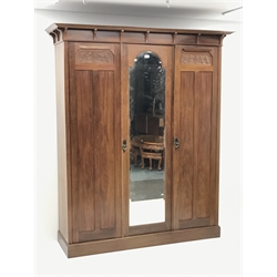 Irish Arts & Crafts walnut triple wardrobe circa 1908, projecting cornice above three doors enclosing fitted interior, single full length bevel edge mirror, platform base, W173cm, H204cm, D56cm
