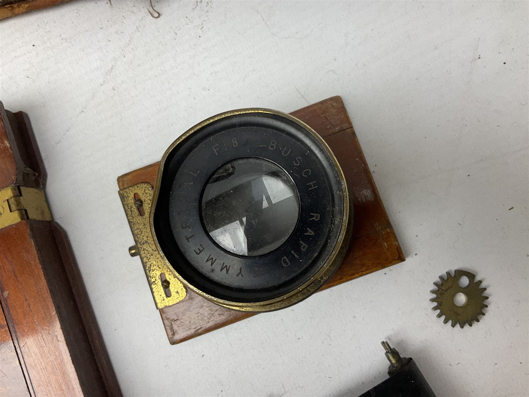 Ensign 'The Sanderson' folding plate camera in mahogany and lacquered brass, field model with canvas wrapped box, two mahogany photographic plates, 'Busch rapid Symmetrical F:8' lens,  and a wooden tripod 