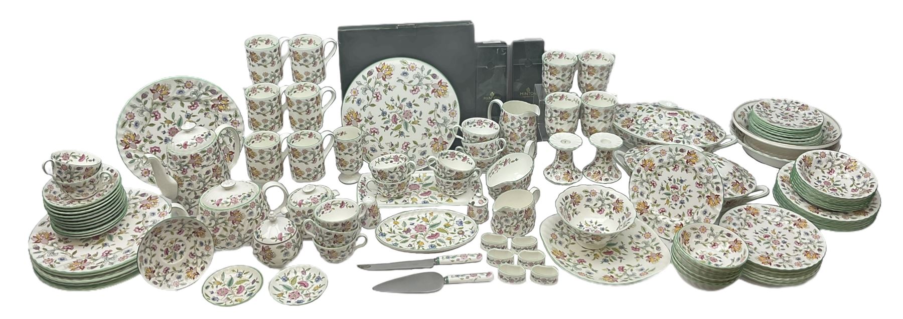 Minton Haddon Hall pattern tea and dinner wares, including basket dish, two covered tureens, six dinner plates, eight dessert plates, twelve tea plates, six soup bowls, six cereal bowls, teapot, coffee pot, milk jug, covered sucrier twelve tea cups and saucers, six mugs, footed bon bon dish, pair of candlestick holders, cake knife and slice etc (81)