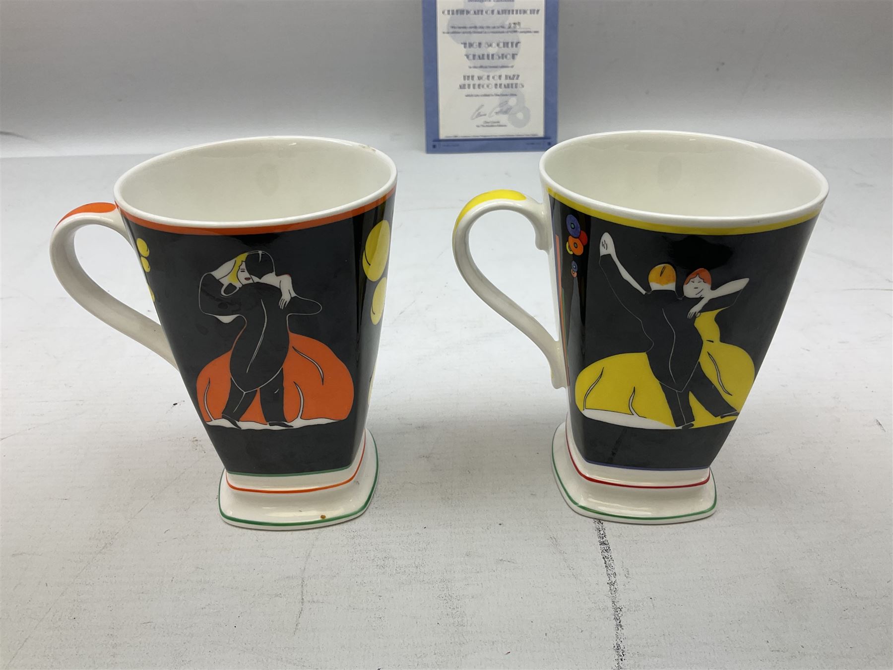 Two limited edition Bradford Exhange Clarice Cliff Age of Jazz beakers, no 289/4,999, with certificate, in box, together with a Moorland Art Deco Clarice Cliff style Huntley Cottage pattern teacup and saucer 