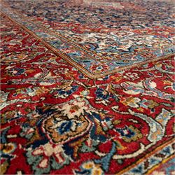 Persian Kashan carpet, navy field with central red diamond medallion enclosing floral rosette, framed by dense scrolling foliage and palmettes, triple borders in red, blue and ivory, originating from central Iran