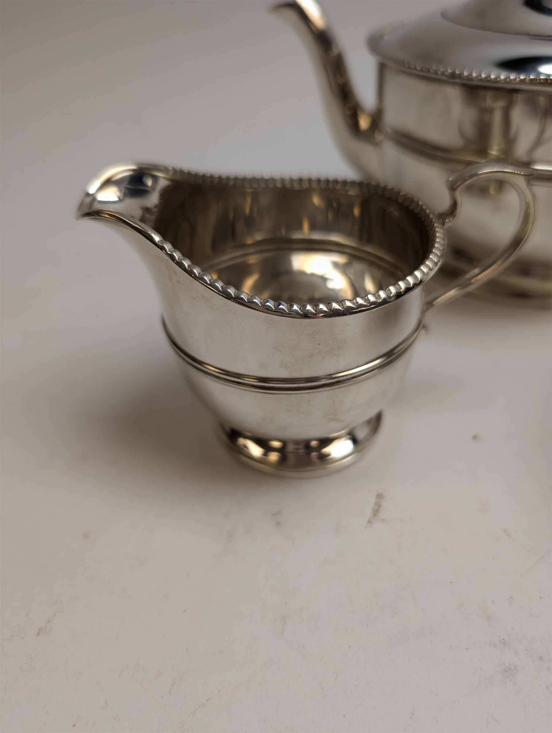 1930s silver three piece tea service, comprising teapot, milk jug and sugar bowl, each of circular form with oblique gadrooned rim, the teapot with Bakelite handle and finial, hallmarked Mappin & Webb Ltd, Birmingham 1931, teapot H14.5cm