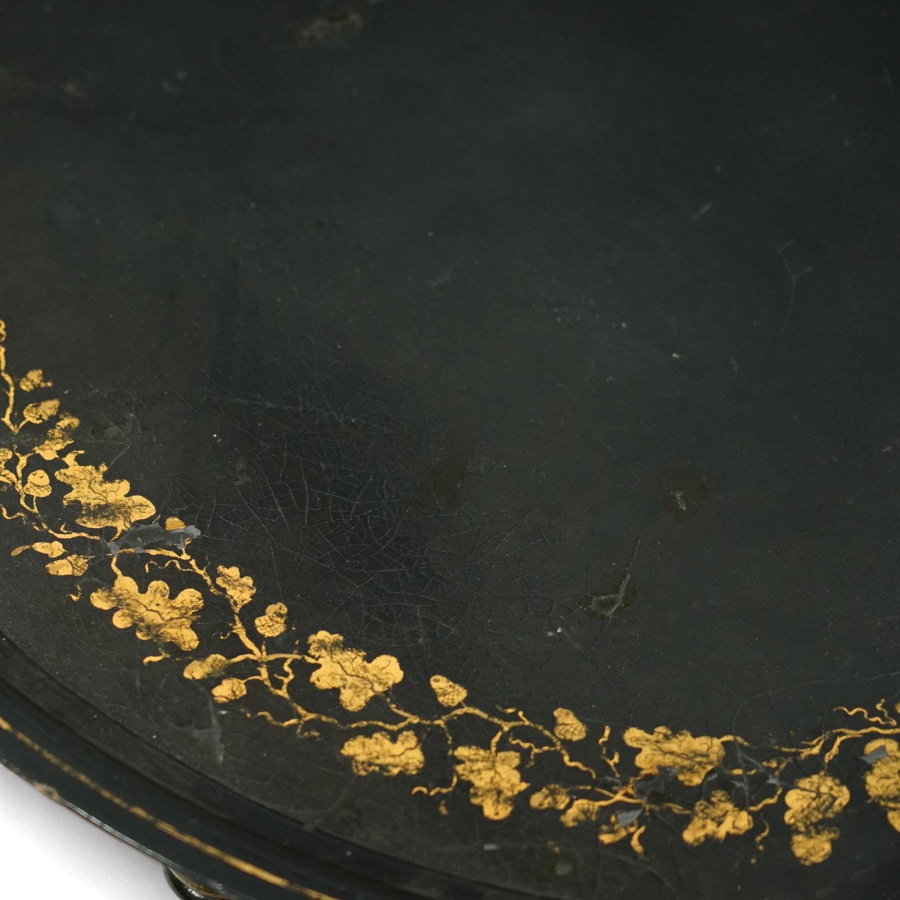 Regency style oval toleware tray table, the black lacquered top with gilt floral decoration, on ebonised faux bamboo frame with stretcher supports