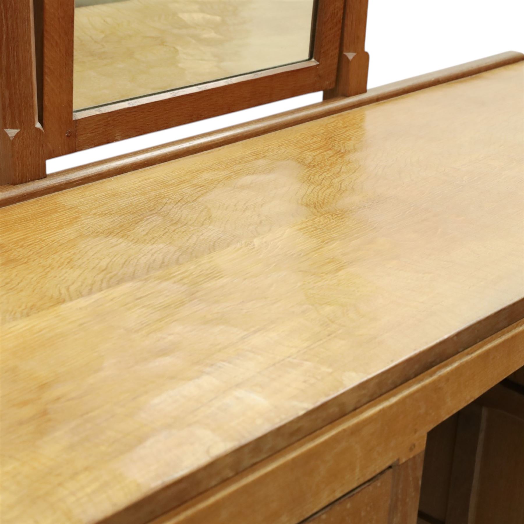 Mouseman - adzed oak kneehole dressing table with mirror, the rectangular adzed top with raised back and canted corners with fixed central pivoting mirror with scallop-carved cresting rail, over an arched recessed kneehole flanked by three graduating drawers to each side with turned knob handles, raised on octagonal feet, with carved mouse signature, by the workshop of Robert Thompson of Kilburn