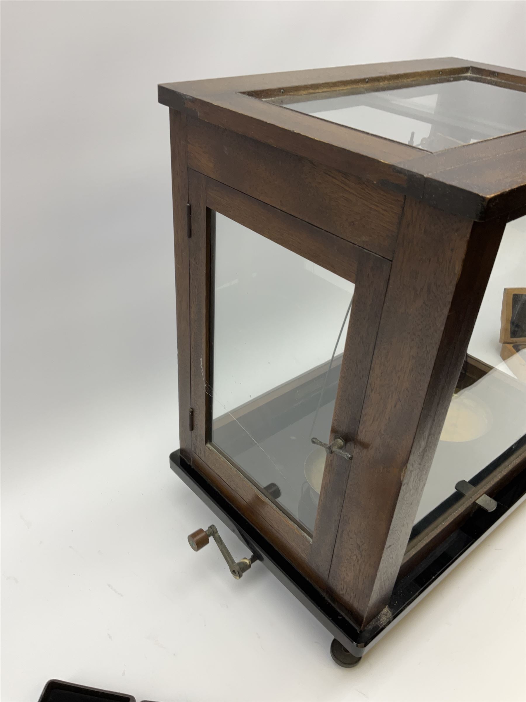 Set of laboratory balance scales by Paul Bunge Hamburg Model 9A No.7977 bearing label for Reynolds & Branson Leeds in mahogany case with upward sliding front door, two hinged side doors, hand cranked rise-and-fall facility and black vitrolite base L36cm H42cm D26cm; and two boxed part sets of weights (3)